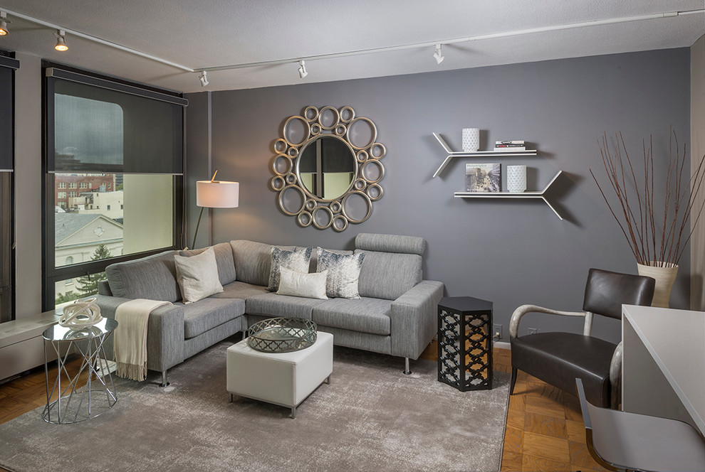 Foto di un piccolo soggiorno contemporaneo chiuso con pareti grigie, parquet chiaro e parete attrezzata