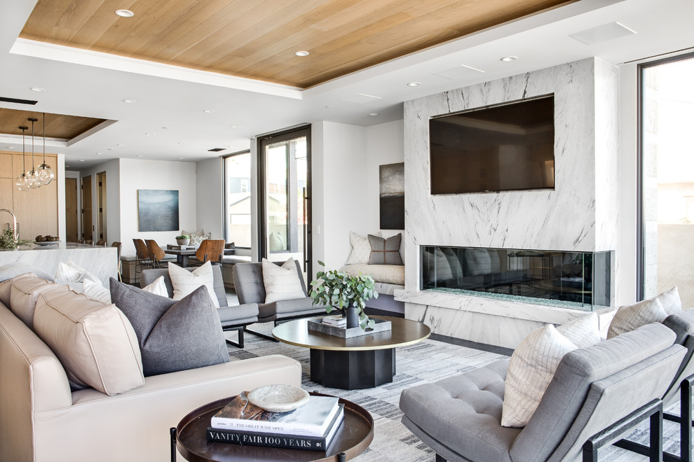 Источник вдохновения для домашнего уюта: открытая гостиная комната в современном стиле с белыми стенами, горизонтальным камином, телевизором на стене и серым полом