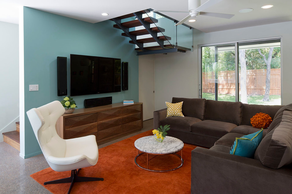 Стильный дизайн: гостиная комната в современном стиле с синими стенами, телевизором на стене и коричневым диваном - последний тренд