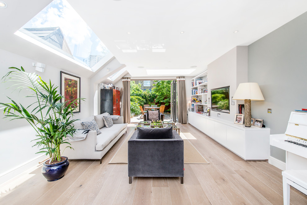 Mittelgroßes, Offenes Modernes Wohnzimmer mit grauer Wandfarbe, hellem Holzboden und TV-Wand in London