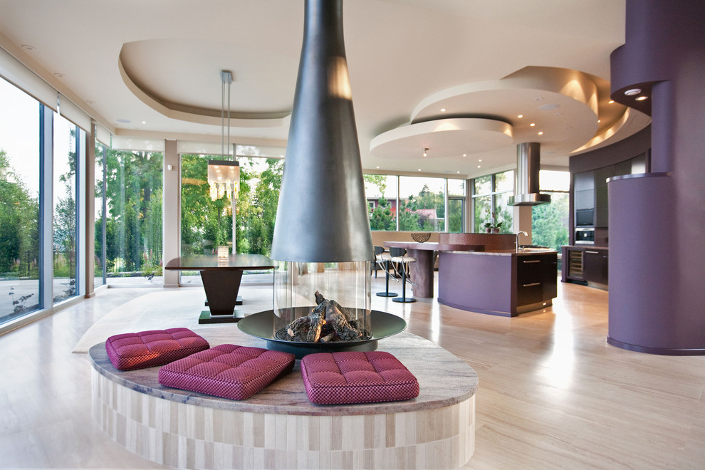 Modelo de salón abierto contemporáneo con paredes púrpuras, chimenea de doble cara y suelo de madera clara