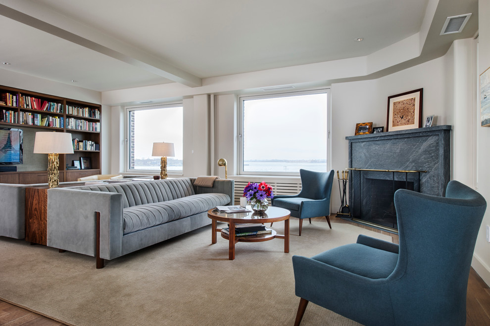 На фото: гостиная комната в современном стиле с угловым камином, синим диваном и ковром на полу с
