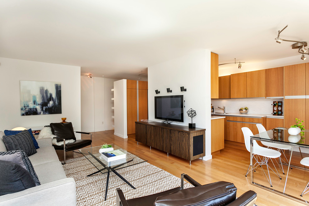 Diseño de salón abierto actual con paredes blancas, suelo de madera en tonos medios y televisor colgado en la pared
