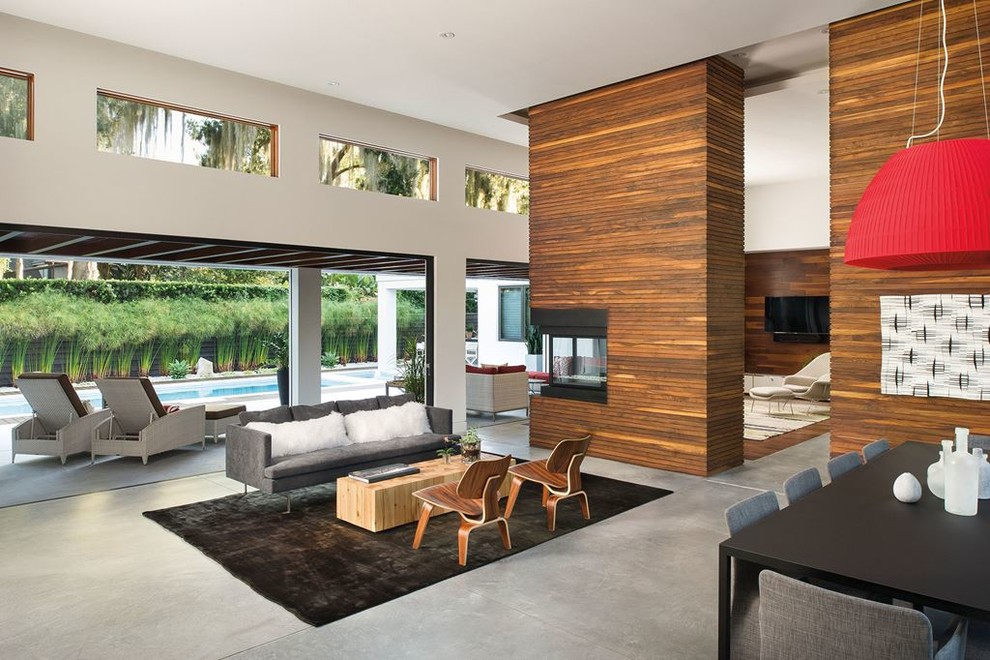 This is an example of a large contemporary open plan living room in Austin with white walls, concrete flooring, a two-sided fireplace, a wooden fireplace surround and a wall mounted tv.
