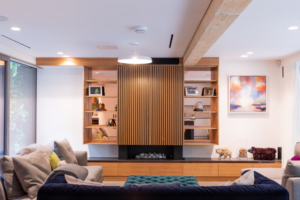 This is an example of a contemporary open plan living room in London with white walls, a stone fireplace surround, a built-in media unit, grey floors, medium hardwood flooring and a standard fireplace.