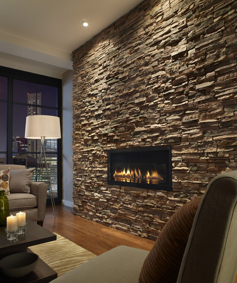На фото: гостиная комната в современном стиле с фасадом камина из камня с