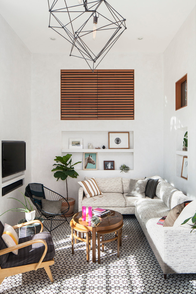 Пример оригинального дизайна: гостиная комната в современном стиле с белыми стенами, телевизором на стене и разноцветным полом