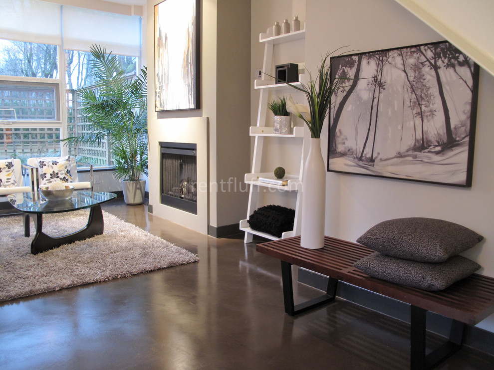 Immagine di un soggiorno contemporaneo con pavimento in cemento e camino classico