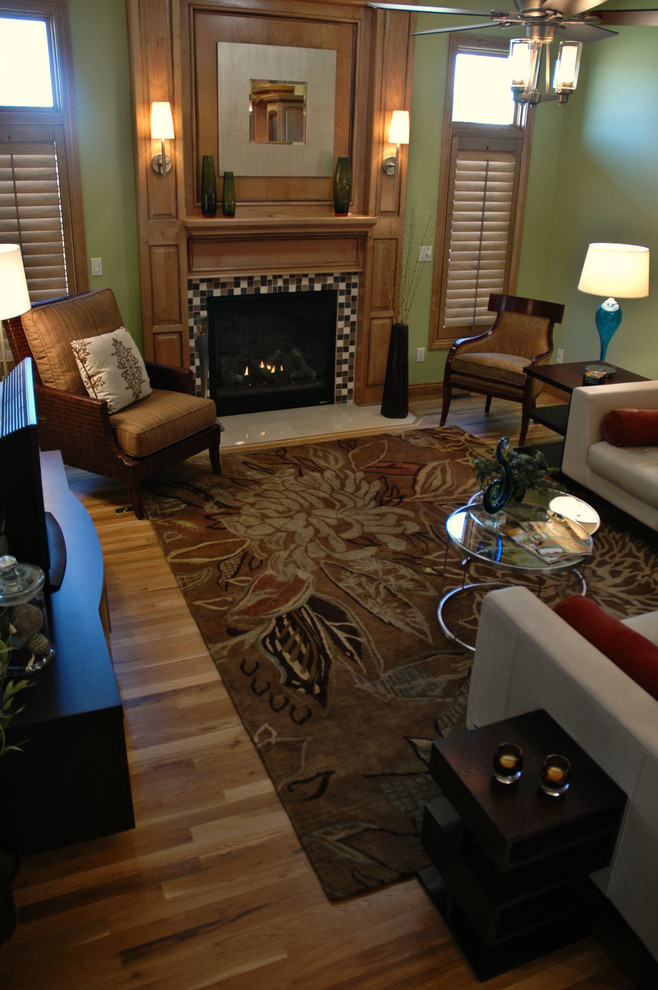 Mittelgroßes, Offenes Modernes Wohnzimmer mit grüner Wandfarbe, braunem Holzboden, Kamin und gefliester Kaminumrandung in Sonstige