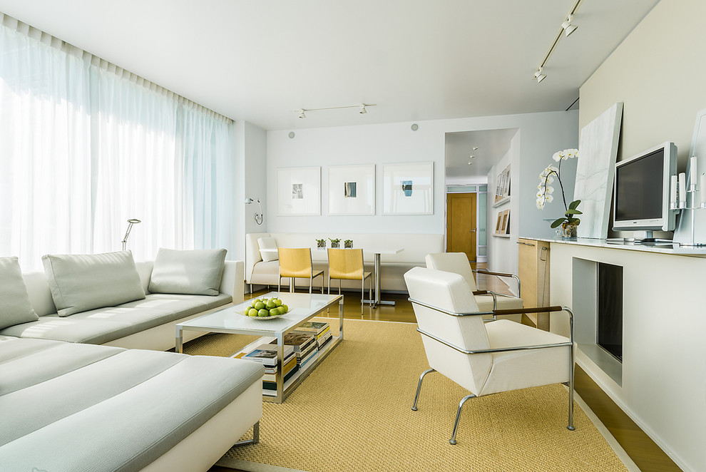 На фото: гостиная комната в современном стиле с белыми стенами и отдельно стоящим телевизором