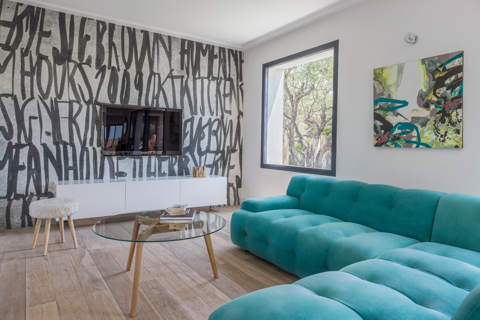 На фото: открытая гостиная комната среднего размера в современном стиле с разноцветными стенами, светлым паркетным полом, телевизором на стене и синим диваном без камина с