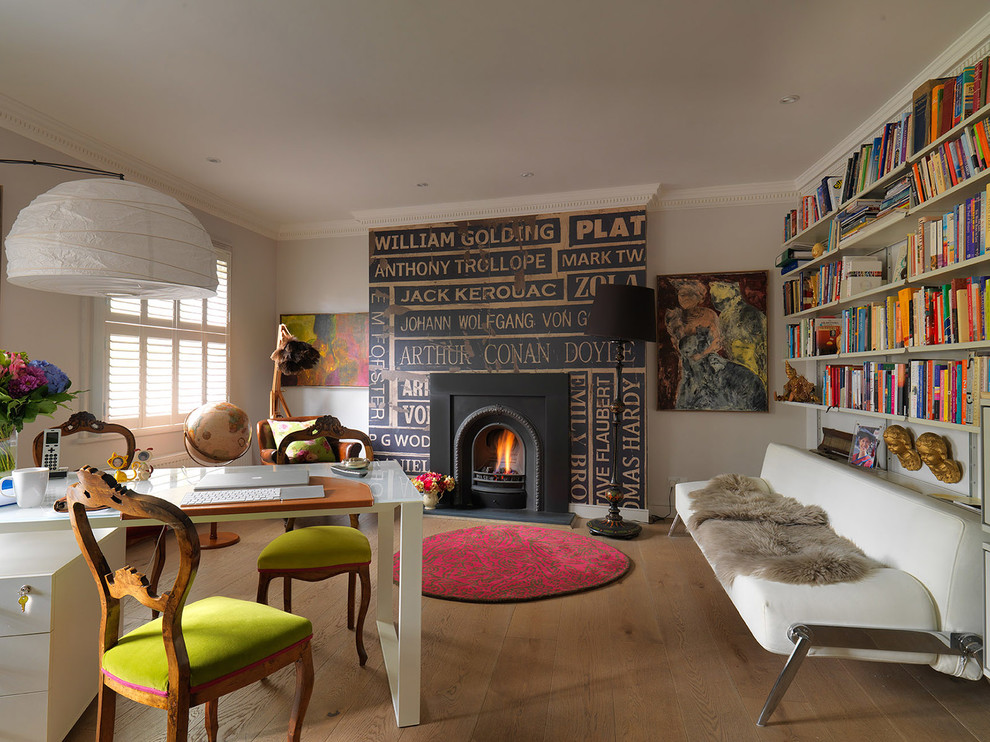 Imagen de biblioteca en casa actual de tamaño medio con paredes grises, suelo de madera en tonos medios, todas las chimeneas y marco de chimenea de metal