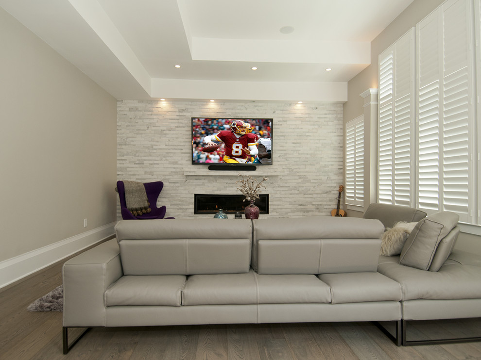 Immagine di un soggiorno contemporaneo di medie dimensioni e chiuso con pareti grigie, parquet scuro, camino classico, cornice del camino in pietra e TV a parete