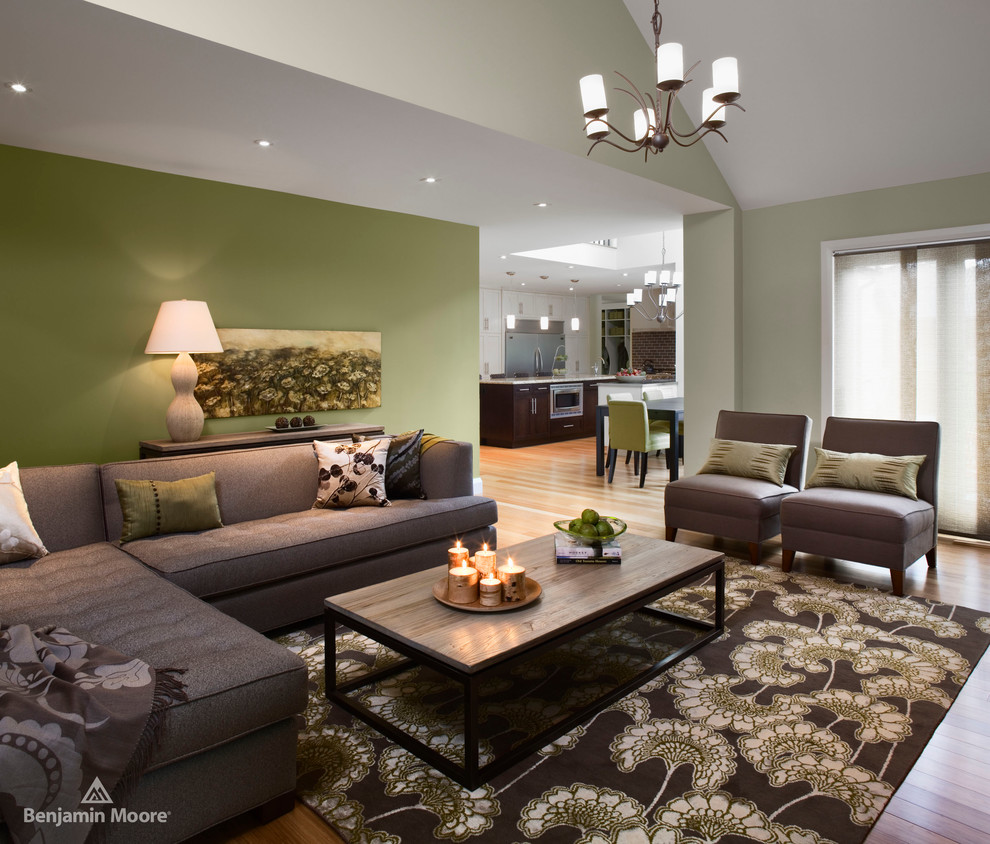 Immagine di un soggiorno design aperto con pareti verdi e parquet chiaro