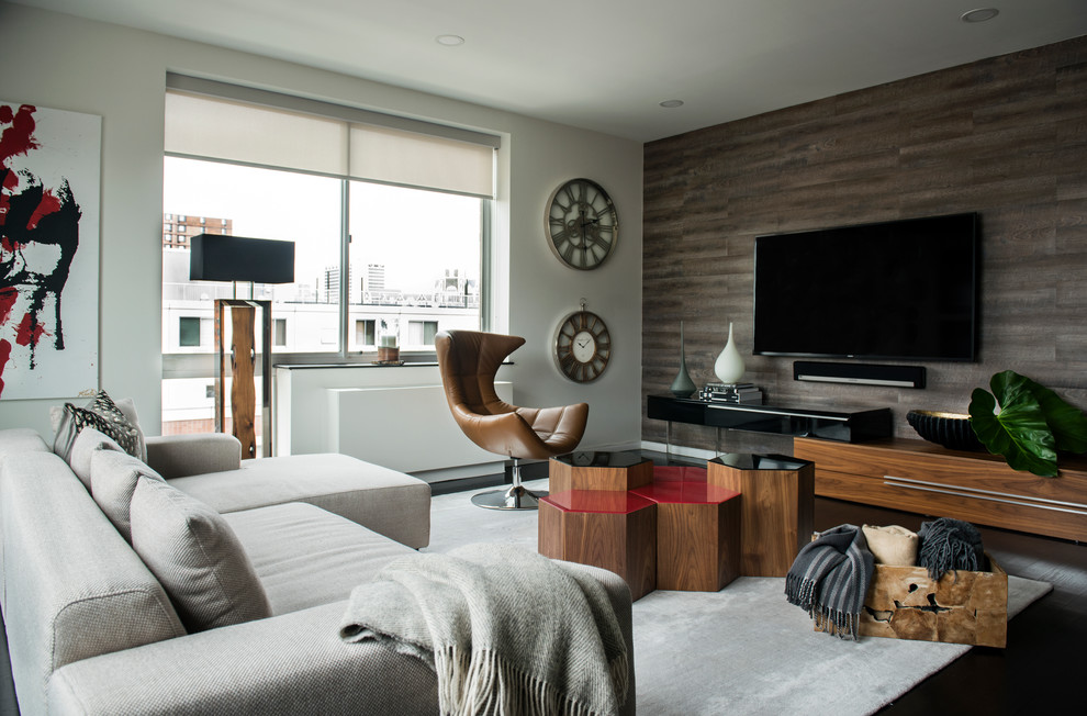 Diseño de salón actual con paredes grises, suelo de madera oscura y televisor colgado en la pared