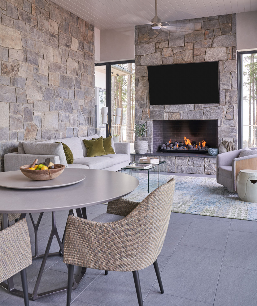 Cette photo montre un salon tendance ouvert avec un mur gris, une cheminée standard, un manteau de cheminée en pierre, un téléviseur fixé au mur, un sol gris et un plafond en lambris de bois.