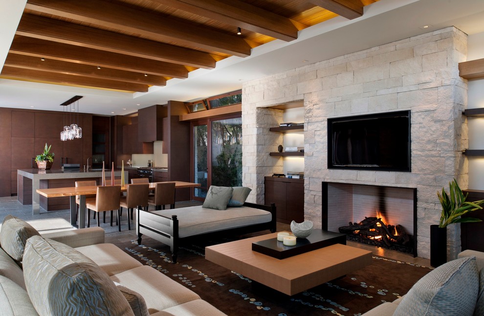 Стильный дизайн: открытая гостиная комната в современном стиле с стандартным камином, телевизором на стене и фасадом камина из камня - последний тренд