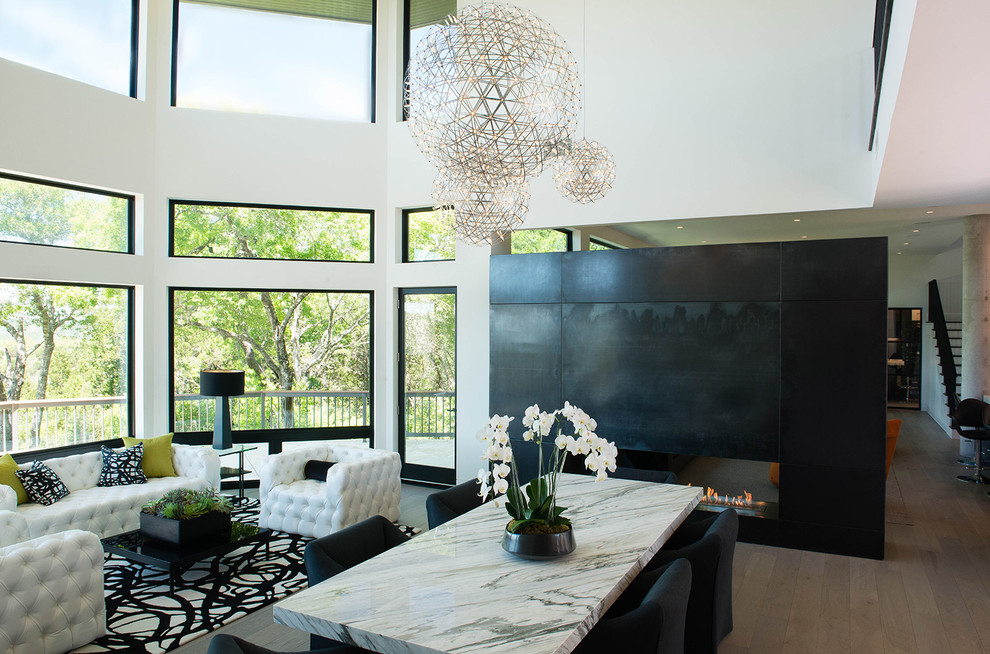Contemporary open plan living room in Austin with white walls, medium hardwood flooring and a two-sided fireplace.