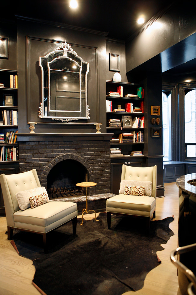 Esempio di un soggiorno minimal con libreria, pareti nere e camino classico