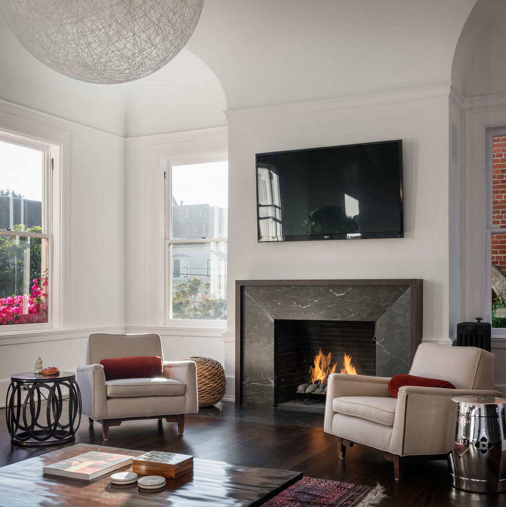 На фото: изолированная гостиная комната в современном стиле с белыми стенами, стандартным камином и телевизором на стене