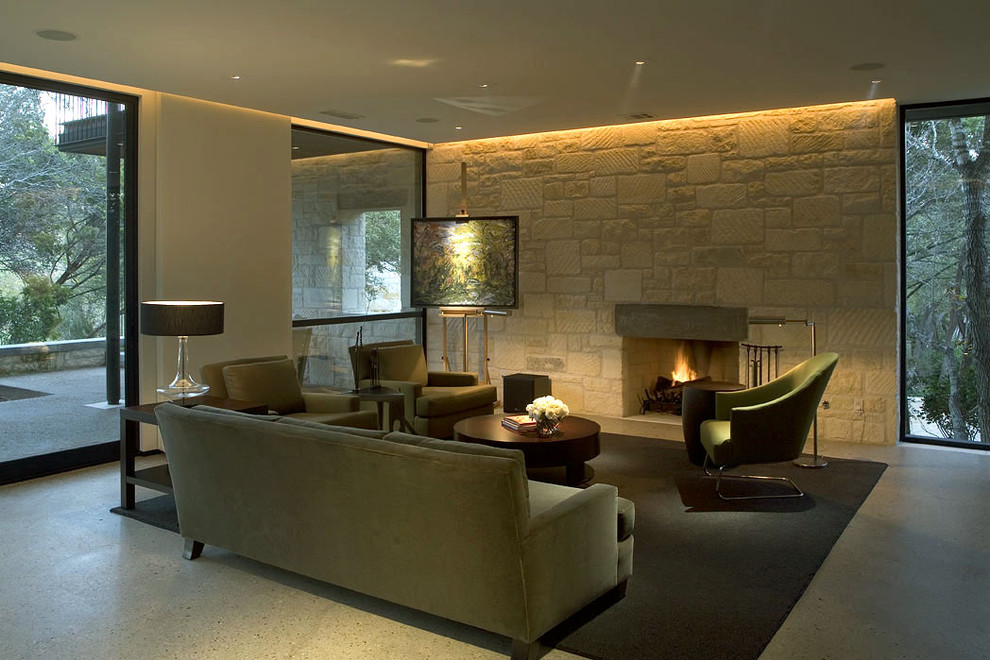 Cette image montre un salon design avec une cheminée standard, un manteau de cheminée en pierre, un mur en pierre et éclairage.