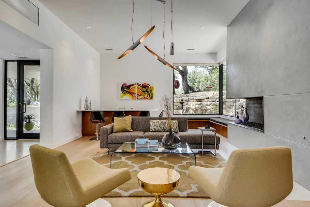 Offenes Modernes Wohnzimmer mit weißer Wandfarbe, hellem Holzboden, Kamin und Kaminumrandung aus Beton in Austin