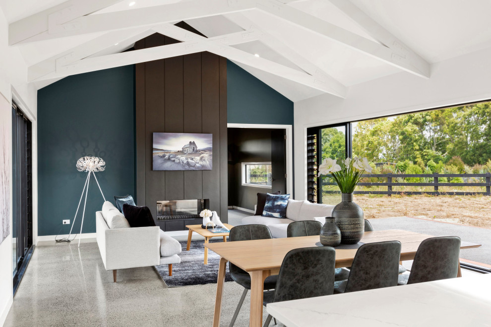 Offenes Modernes Wohnzimmer mit blauer Wandfarbe, Betonboden, Tunnelkamin, TV-Wand und grauem Boden in Hamilton