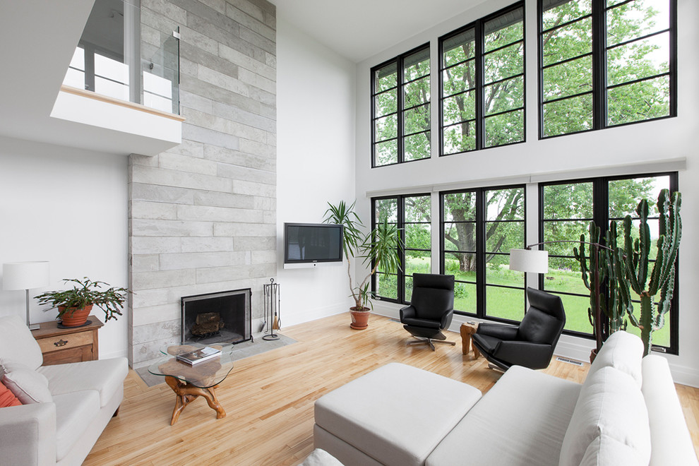 Idée de décoration pour un grand salon design ouvert avec un mur blanc, parquet clair, une cheminée standard et un manteau de cheminée en béton.