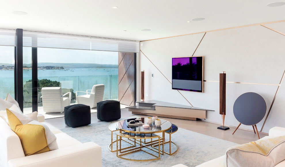 Imagen de salón actual con paredes blancas, suelo de madera en tonos medios y televisor colgado en la pared