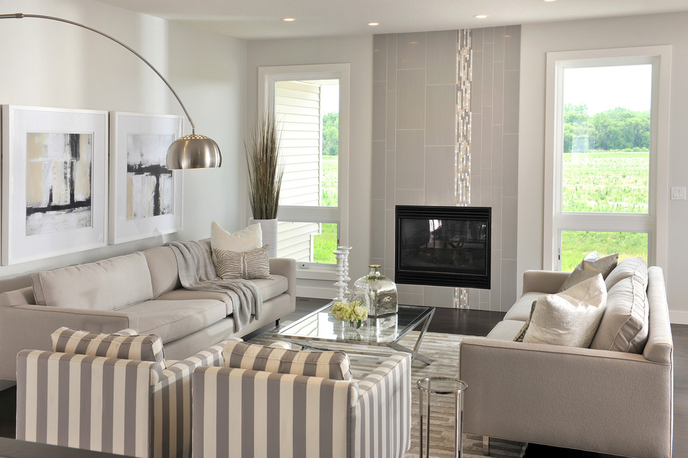 Идея дизайна: открытая гостиная комната в современном стиле с белыми стенами, темным паркетным полом, стандартным камином, фасадом камина из плитки и коричневым полом без телевизора
