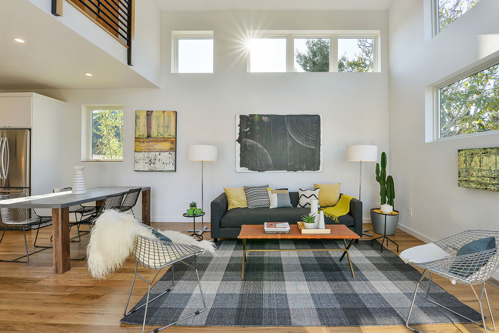 This is an example of a contemporary open plan living room in San Francisco with white walls and light hardwood flooring.