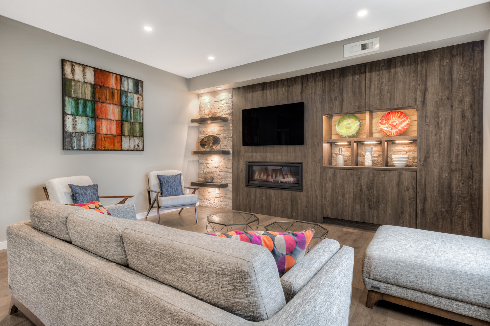 Diseño de salón abierto contemporáneo con paredes grises, suelo de madera oscura, chimenea lineal, televisor colgado en la pared y suelo marrón