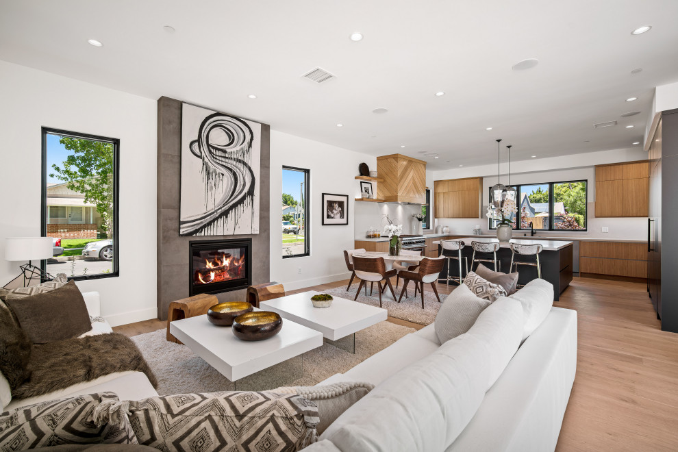 Inspiration for a contemporary open concept medium tone wood floor and brown floor living room remodel in Los Angeles with white walls and a standard fireplace