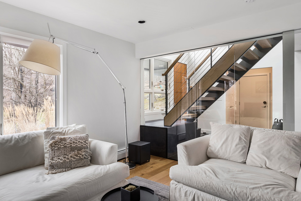 Foto di un soggiorno minimal di medie dimensioni e aperto con pareti bianche, parquet chiaro, TV a parete e pavimento beige