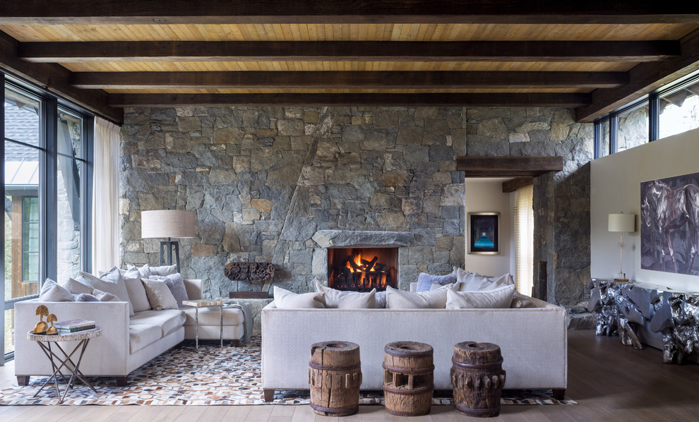 Diseño de salón para visitas abierto rústico con suelo de madera clara, todas las chimeneas, marco de chimenea de piedra, suelo beige, piedra y vigas vistas