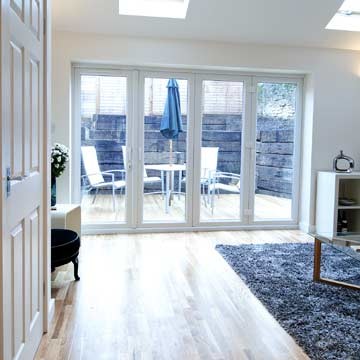 Modelo de salón para visitas abierto actual de tamaño medio sin chimenea con paredes blancas y suelo de madera en tonos medios