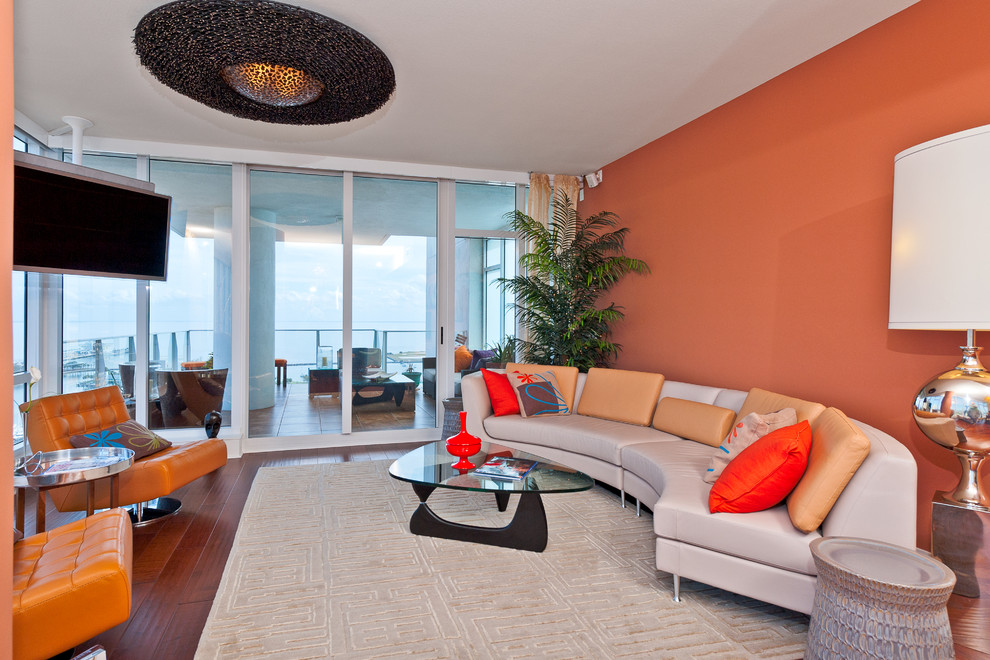 Пример оригинального дизайна: гостиная комната в современном стиле с оранжевыми стенами и телевизором на стене