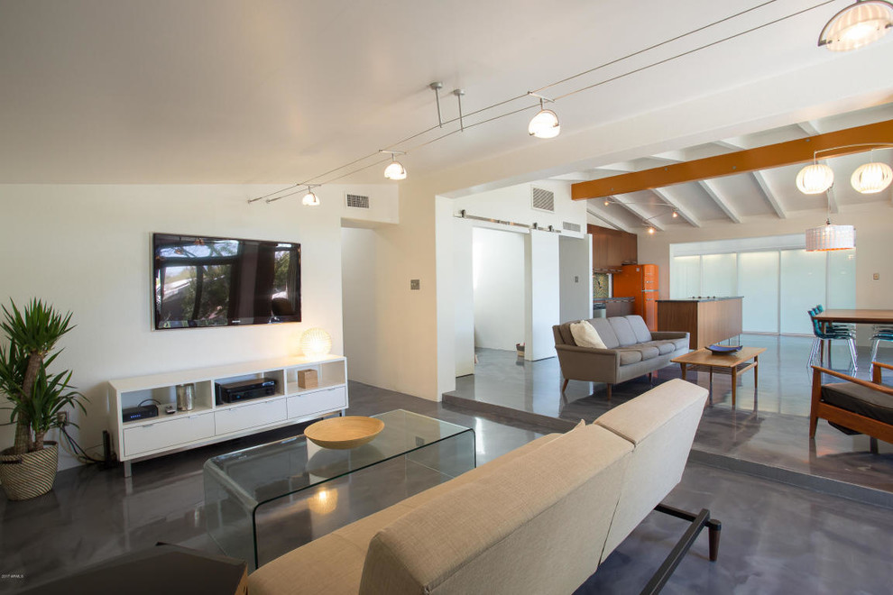 Пример оригинального дизайна: большая открытая гостиная комната в стиле ретро с бетонным полом, белыми стенами, телевизором на стене, стандартным камином, фасадом камина из бетона и серым полом