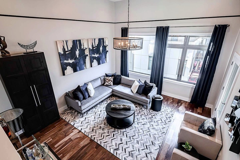 Immagine di un grande soggiorno minimal stile loft con pareti beige, pavimento in legno massello medio, camino sospeso, cornice del camino in metallo, nessuna TV e pavimento marrone
