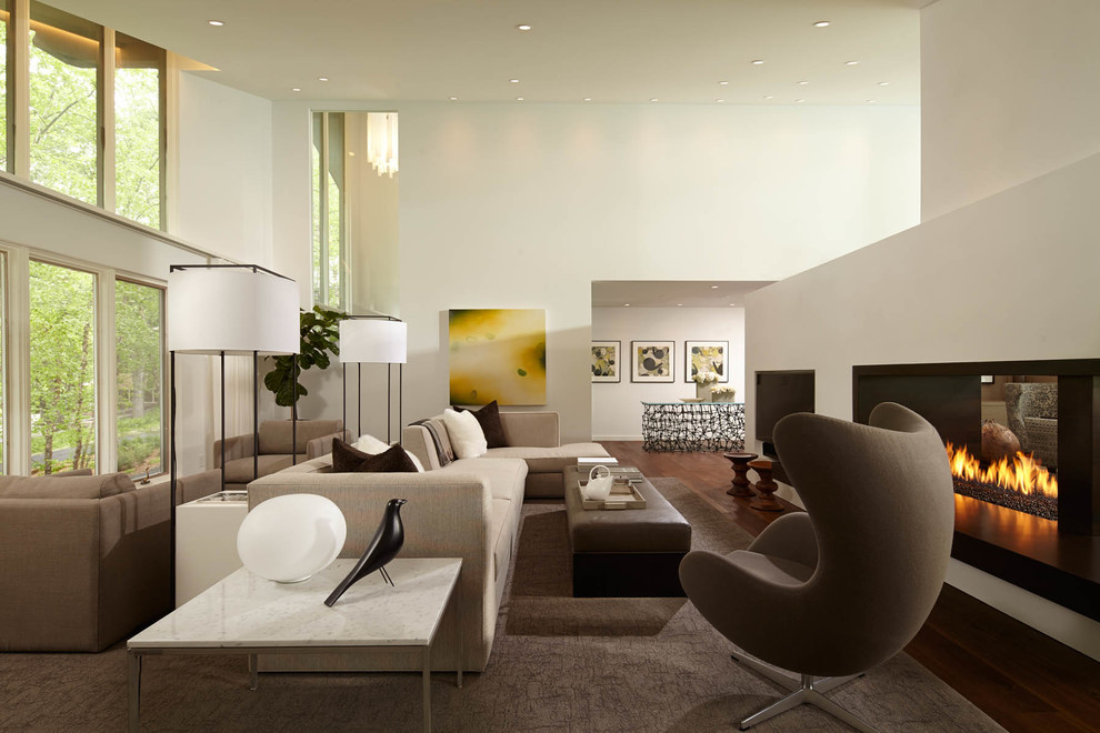 Идея дизайна: большая парадная, открытая гостиная комната в современном стиле с паркетным полом среднего тона, двусторонним камином, белыми стенами и ковром на полу