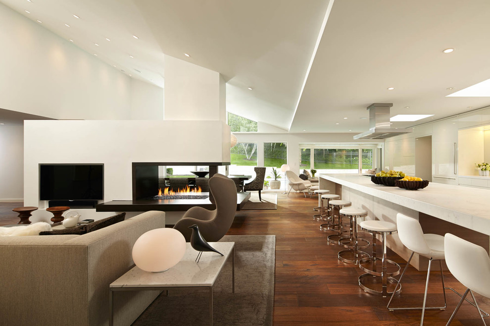 Exemple d'un grand salon tendance ouvert avec une salle de réception, un mur blanc, un sol en bois brun et une cheminée double-face.