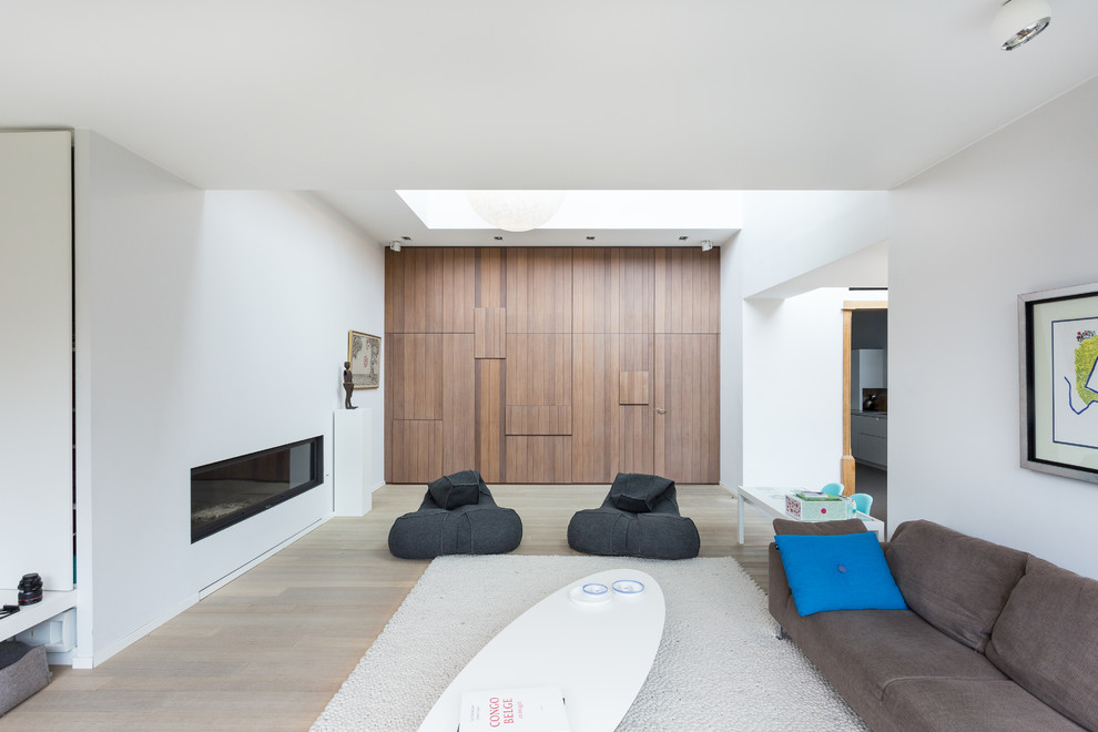Inspiration för minimalistiska separata vardagsrum, med ett finrum, vita väggar, ljust trägolv och en bred öppen spis