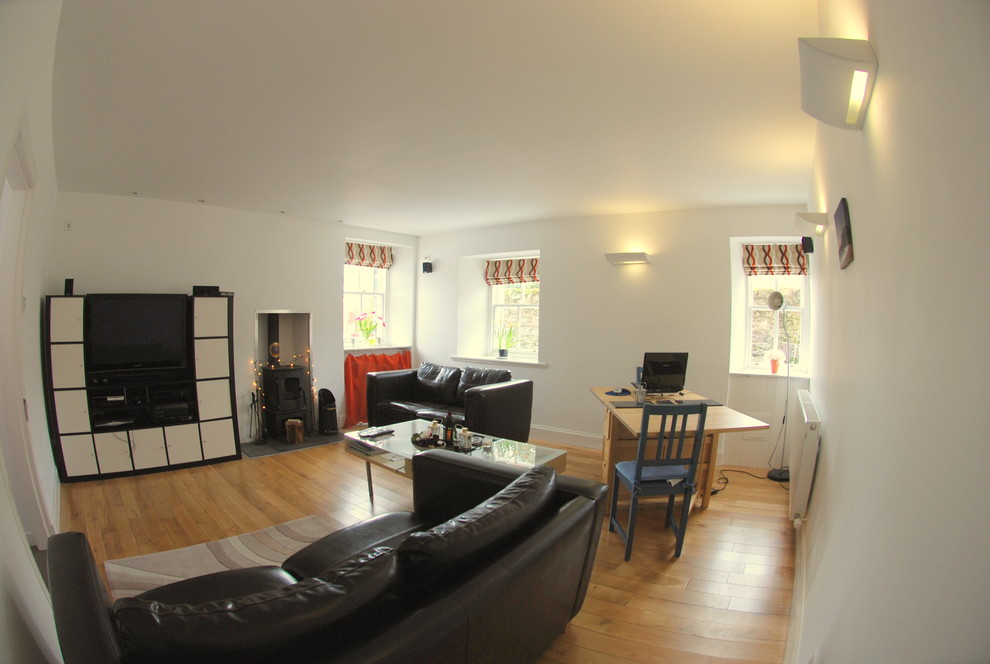 Cette image montre un salon design avec un mur blanc, un sol en bois brun, un poêle à bois et un téléviseur indépendant.