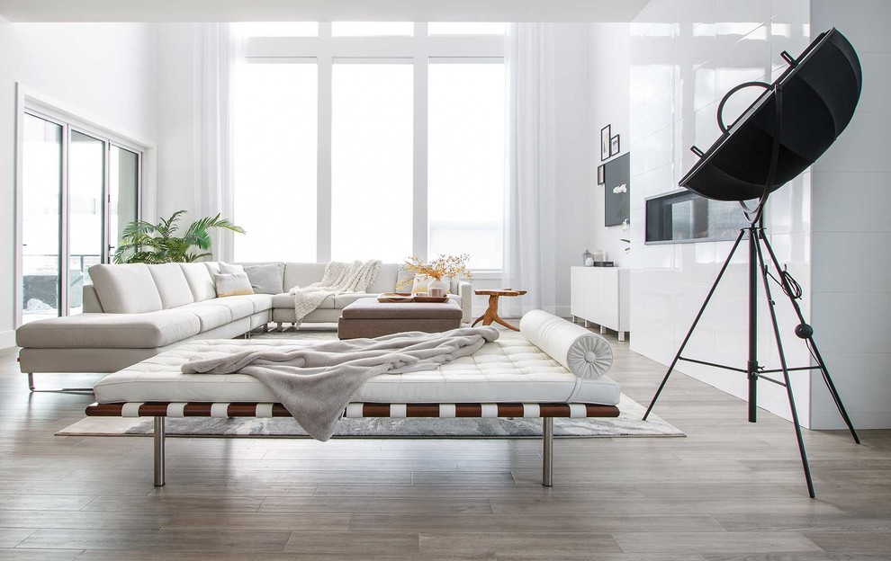 Großes, Offenes Modernes Wohnzimmer mit weißer Wandfarbe, hellem Holzboden, Gaskamin, gefliester Kaminumrandung, TV-Wand und braunem Boden in Calgary