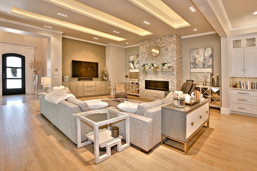 Idee per un grande soggiorno minimal aperto con pareti beige, parquet chiaro, camino classico, cornice del camino in pietra e TV a parete