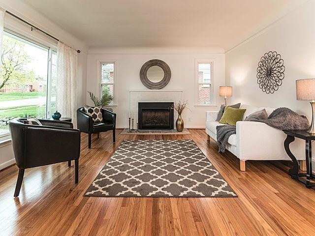 Example of a large trendy formal and open concept medium tone wood floor and brown floor living room design in Detroit with white walls, a standard fireplace, a brick fireplace and no tv