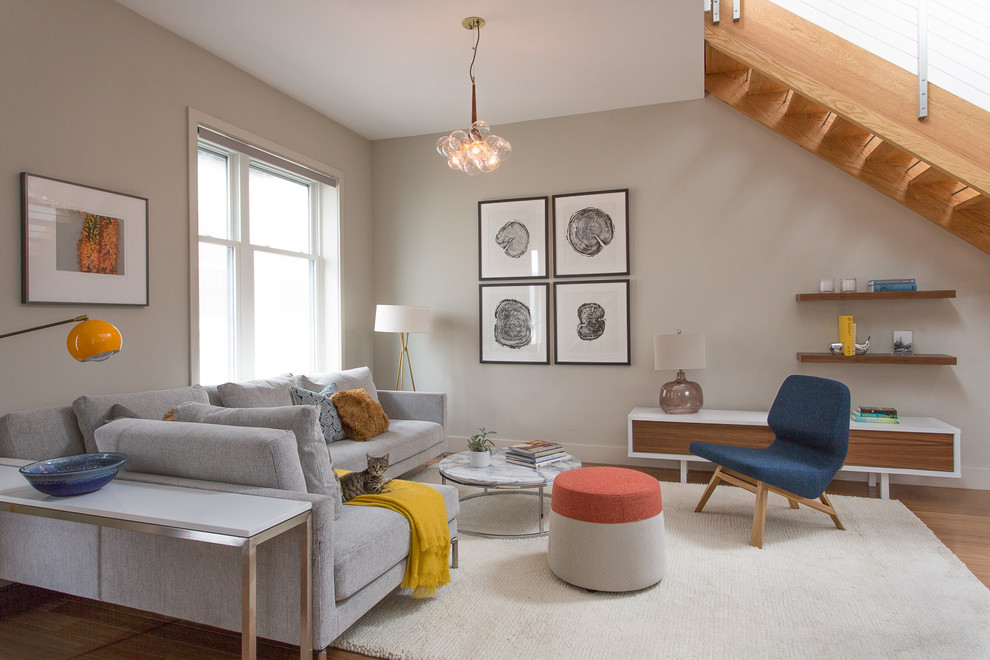 Immagine di un soggiorno contemporaneo aperto con pareti grigie e parquet chiaro