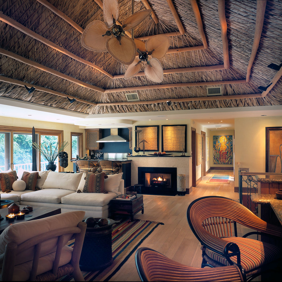 Immagine di un grande soggiorno tropicale aperto con pareti gialle, parquet chiaro, camino classico, cornice del camino in metallo e nessuna TV
