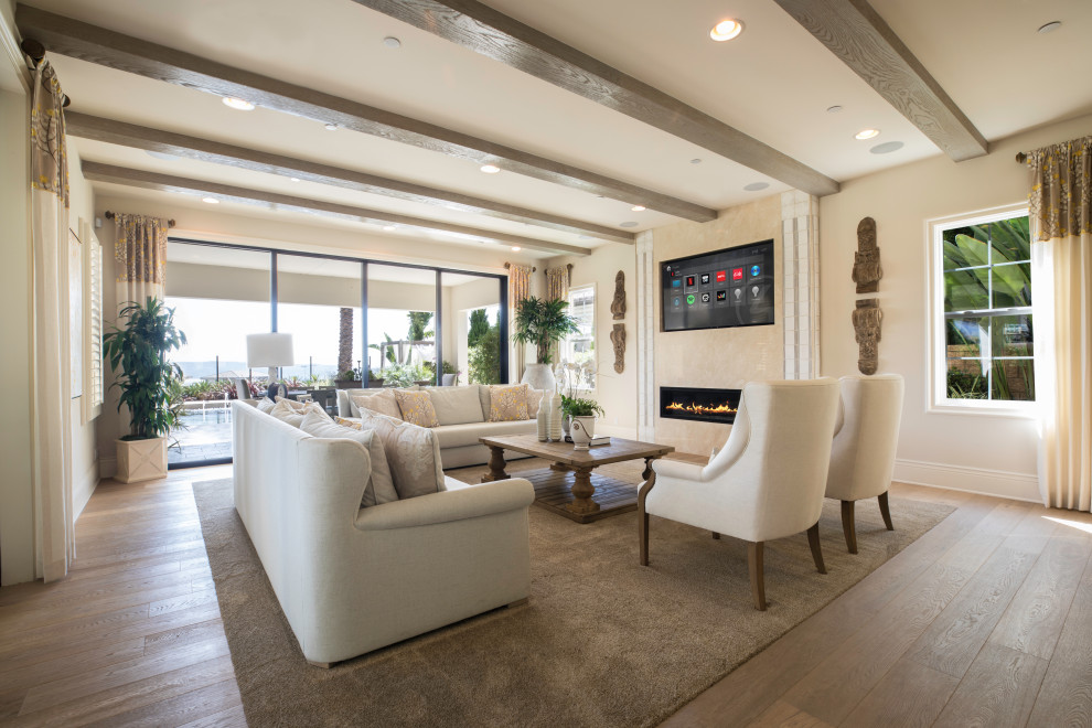 Ejemplo de salón tradicional renovado con paredes beige, suelo de madera en tonos medios, chimenea lineal, televisor colgado en la pared, suelo marrón y vigas vistas
