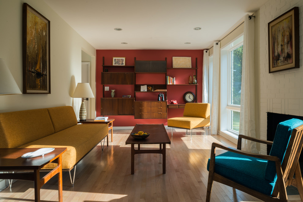 Immagine di un soggiorno minimalista di medie dimensioni con pareti rosse, parquet chiaro, pavimento beige, camino classico, cornice del camino in mattoni e nessuna TV